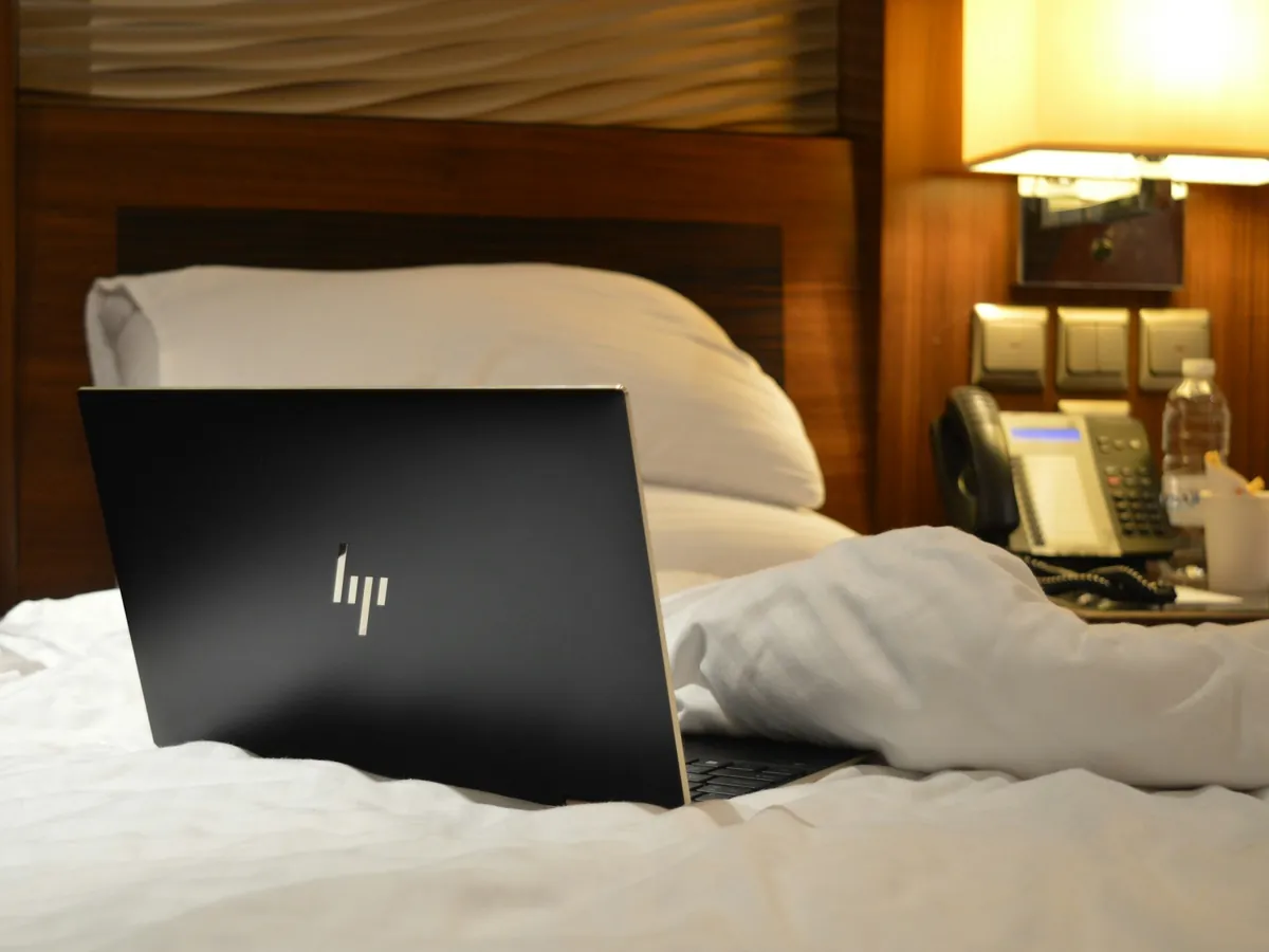 A laptop open on a bed in a hotel room